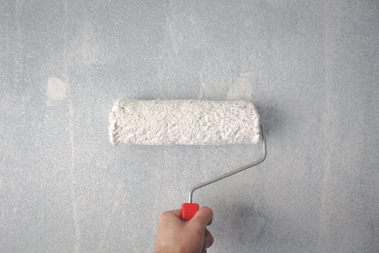 The Art of Drawing Readers In: Your attractive post title goes here A person's hand using a paint roller to apply white paint on a wall.